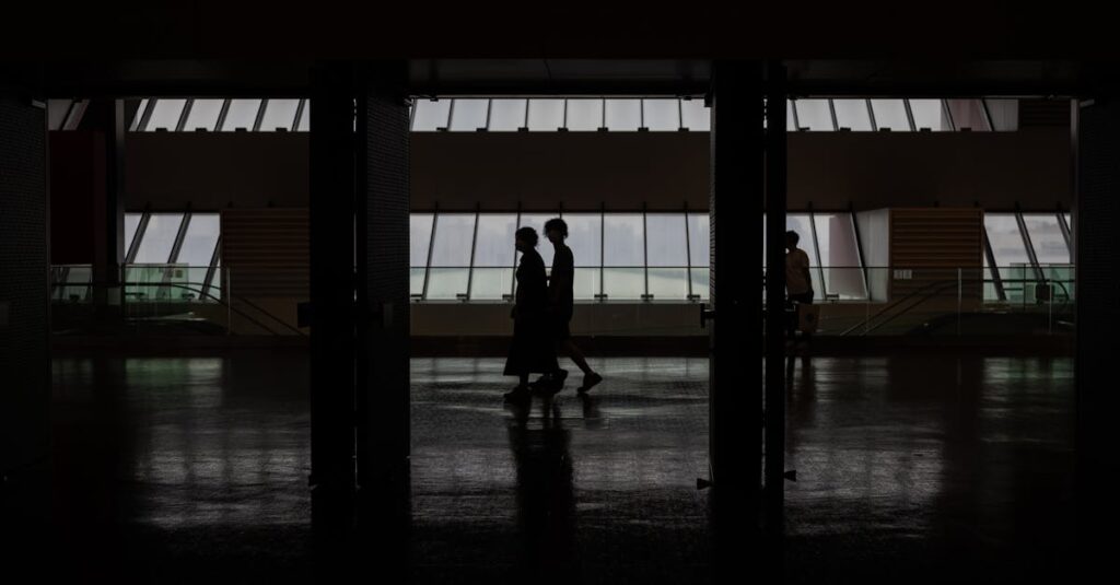 Silhouette of people walking through a modern hallway with large windows in Shanghai, China.