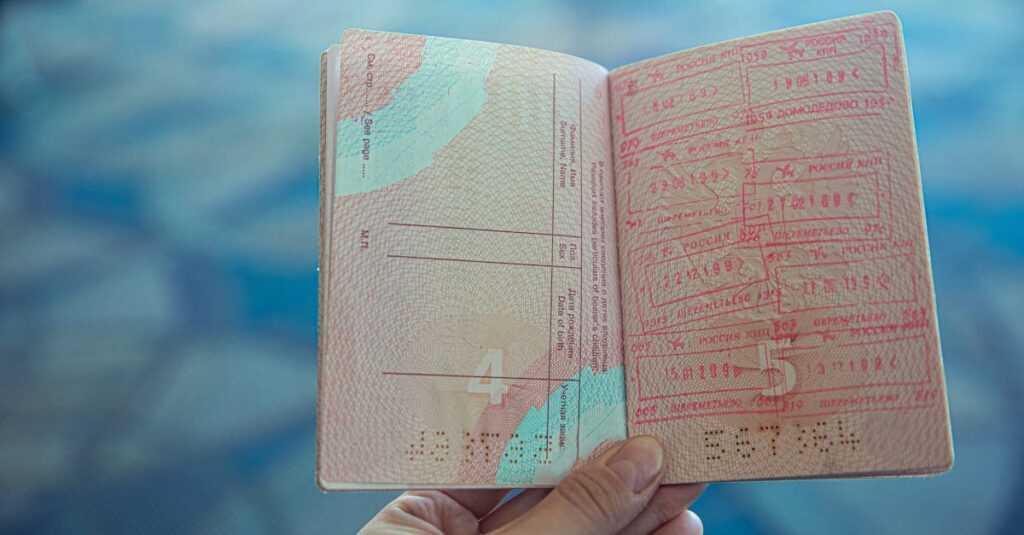 Close-up view of an open passport displaying various travel stamps in an airport setting.